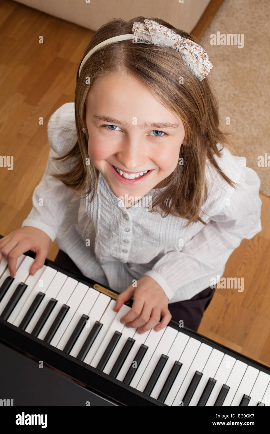 Photo of a happy young girl playing the piano at home. Stock Photo