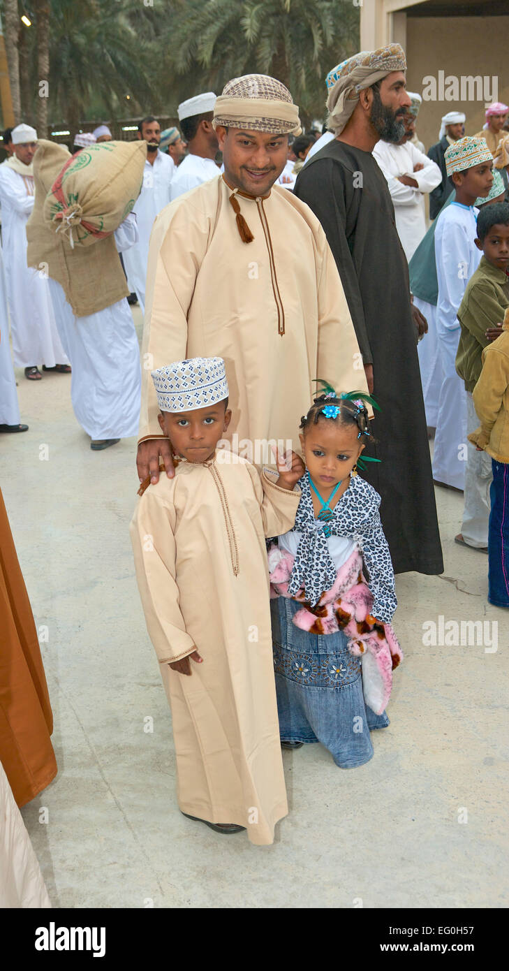 A proud Omani father with his two young children, all immaculately dressed in traditional clothing, in Muscat in Oman. Stock Photo