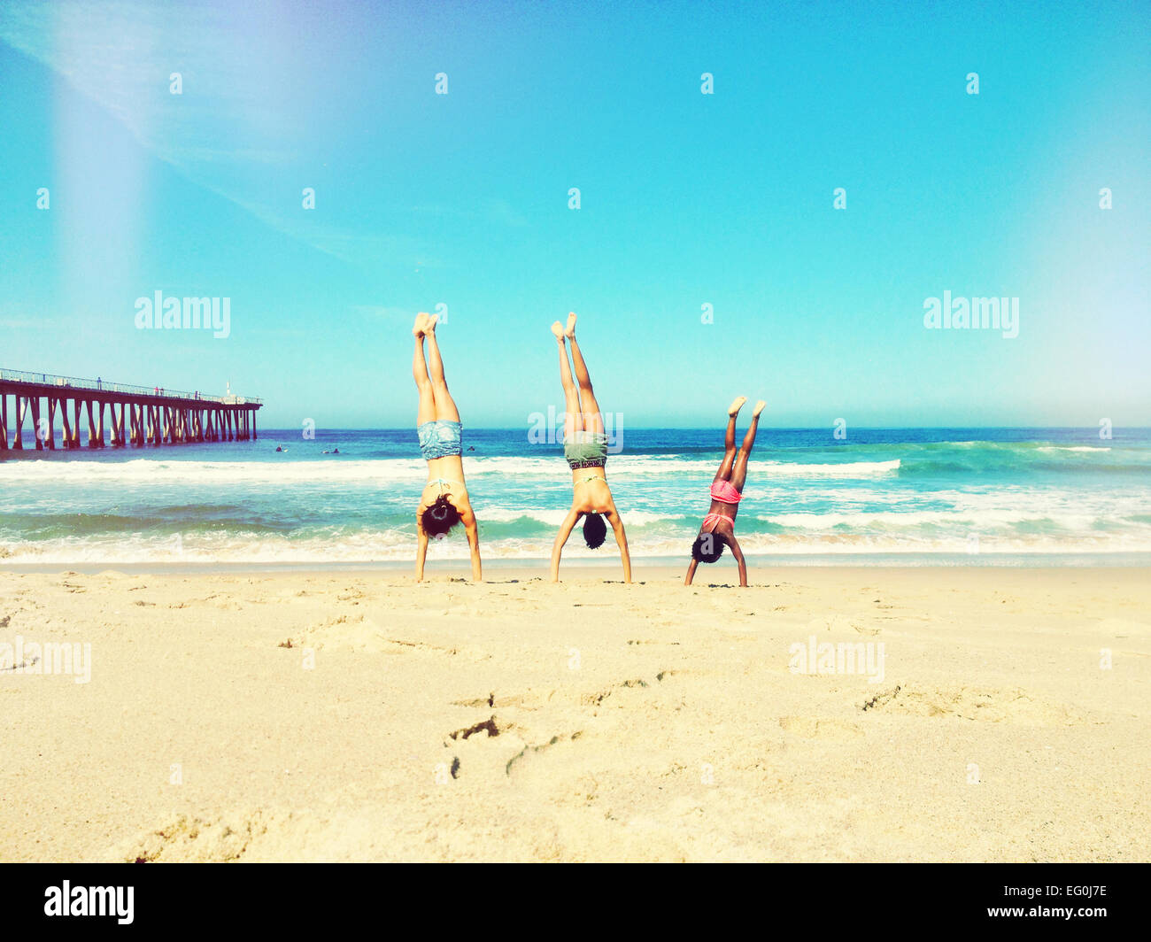 Mother, father and daughter doing handstand on beach Stock Photo