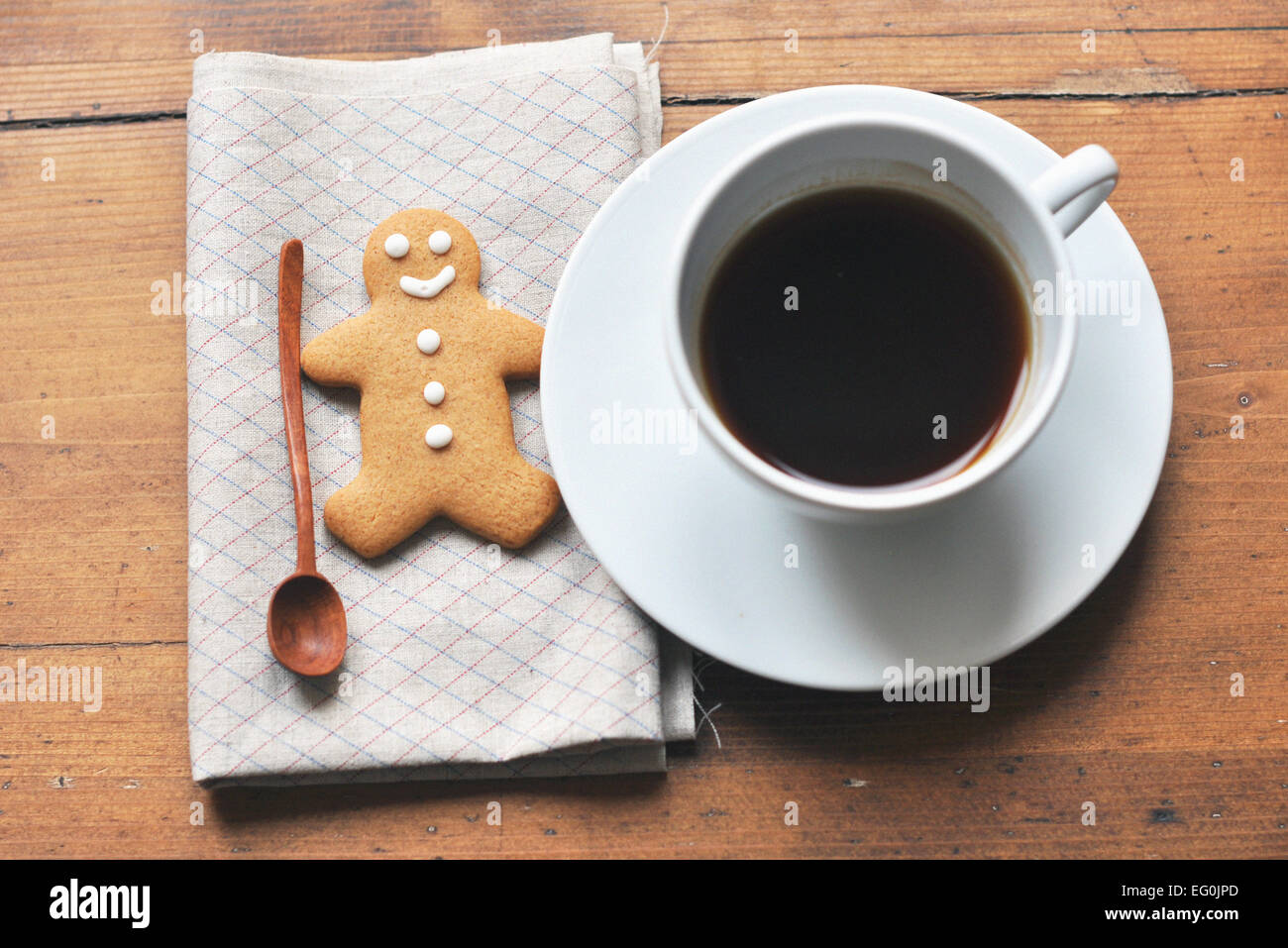 Cup of coffee and gingerbread man with spoon on wooden table Stock Photo