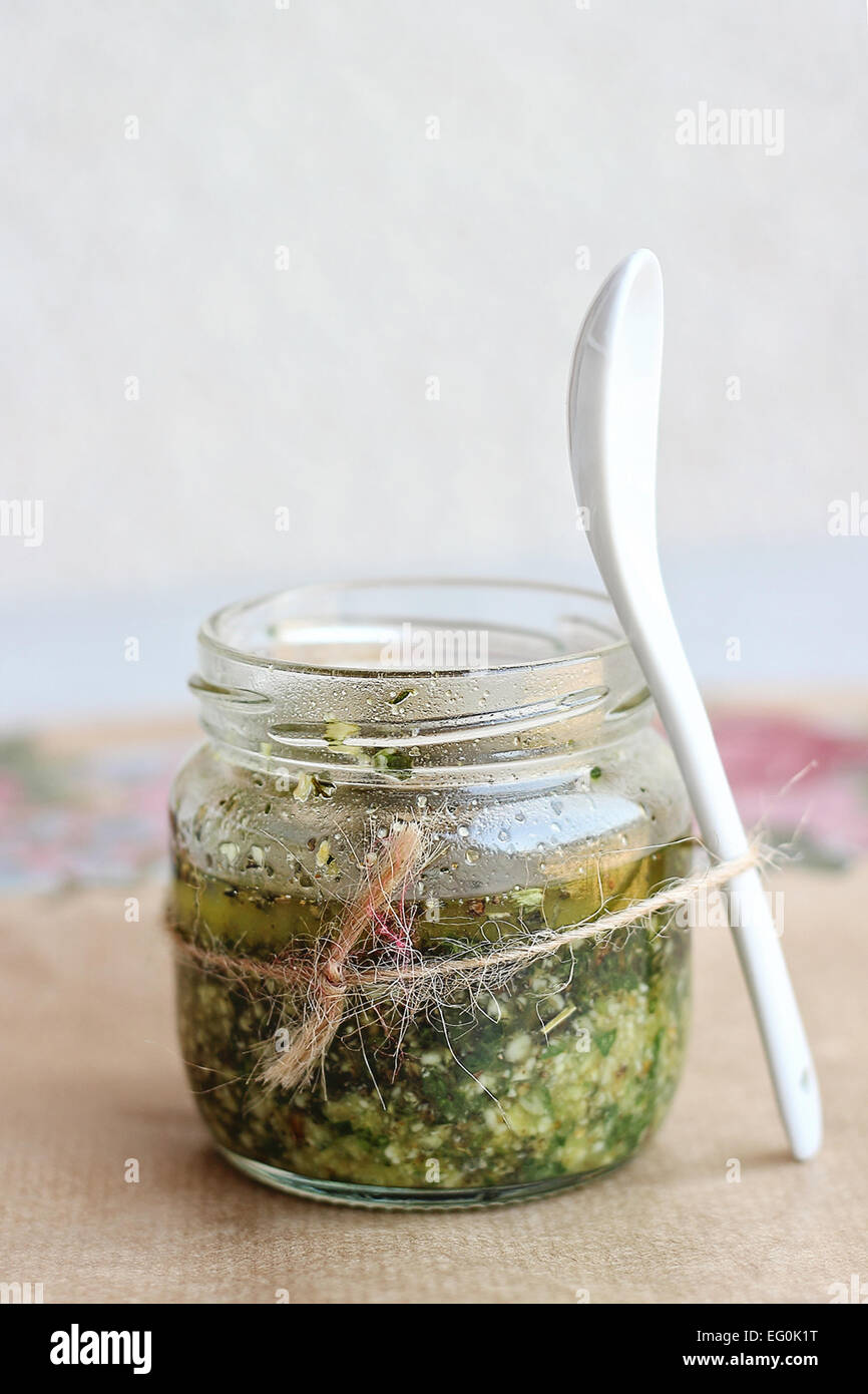 Homemade pesto sauce in glass jar and porcelain spoon Stock Photo