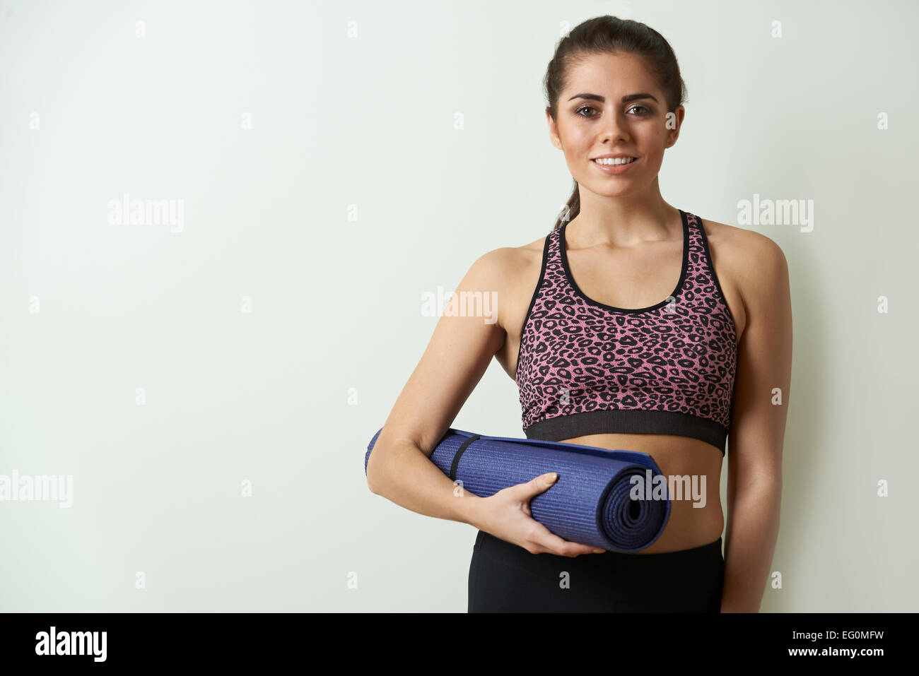 Young Woman In Sportswear Carrying Exercise Mat Stock Photo