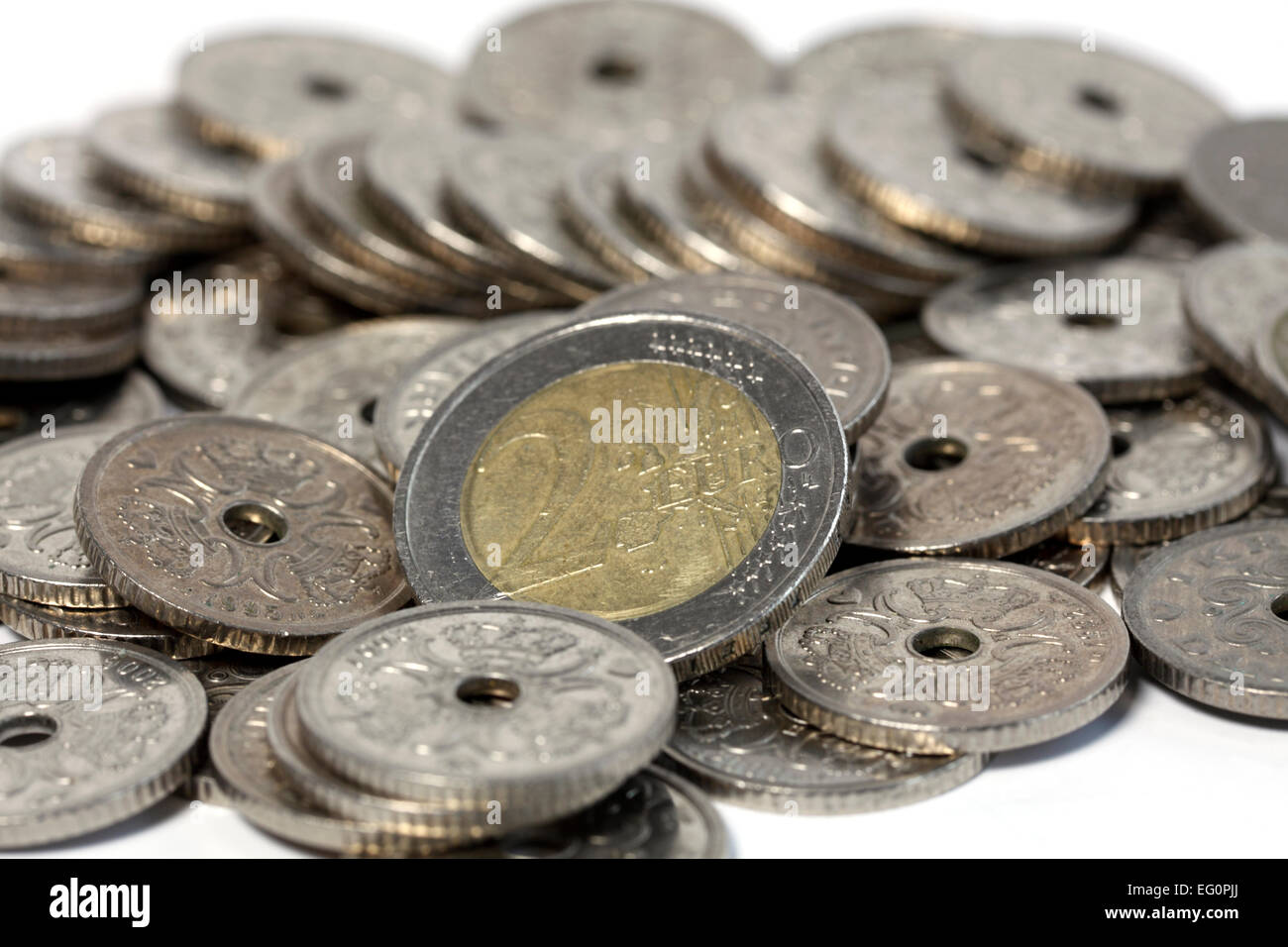 Euros balancing in the midst of Danish Kroner. A 2 Euro piece in the midst of Danish 1 Krone pieces on white. Stock Photo