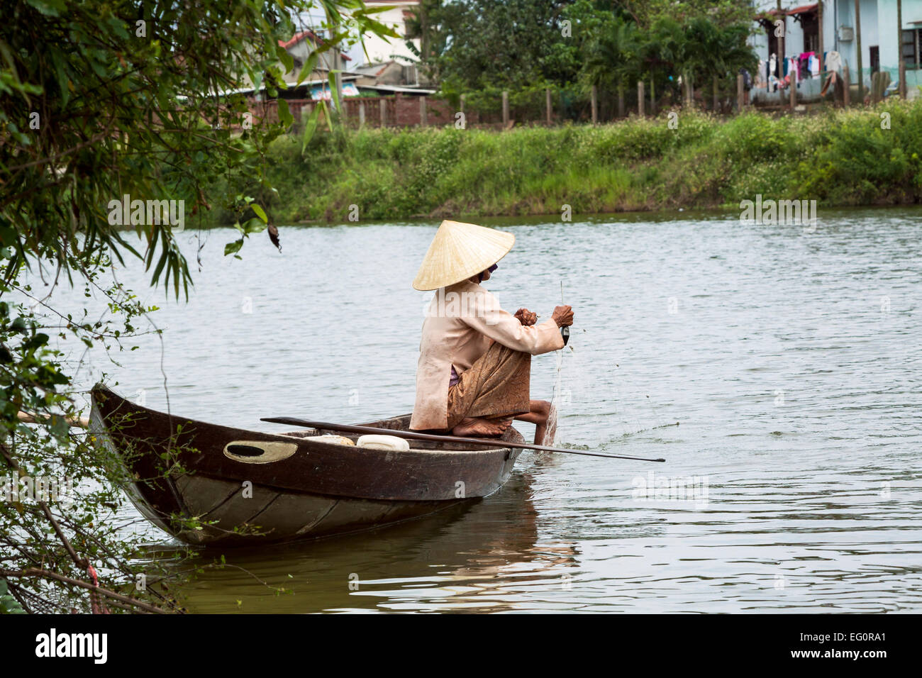 Traditionally dressed old woman fishing from her small fishing boat, Hoi An, Vietnam, Indochina, Southeast Asia, Asia Stock Photo