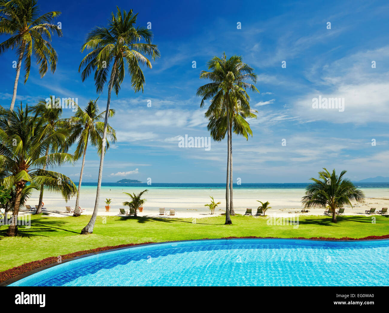 Tropical beach with coconut palms and swimming pool Stock Photo