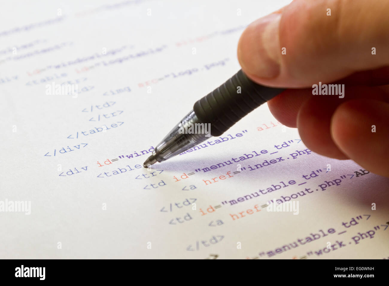 A programmer / man pointing with his pen at HTML code for a web page ...