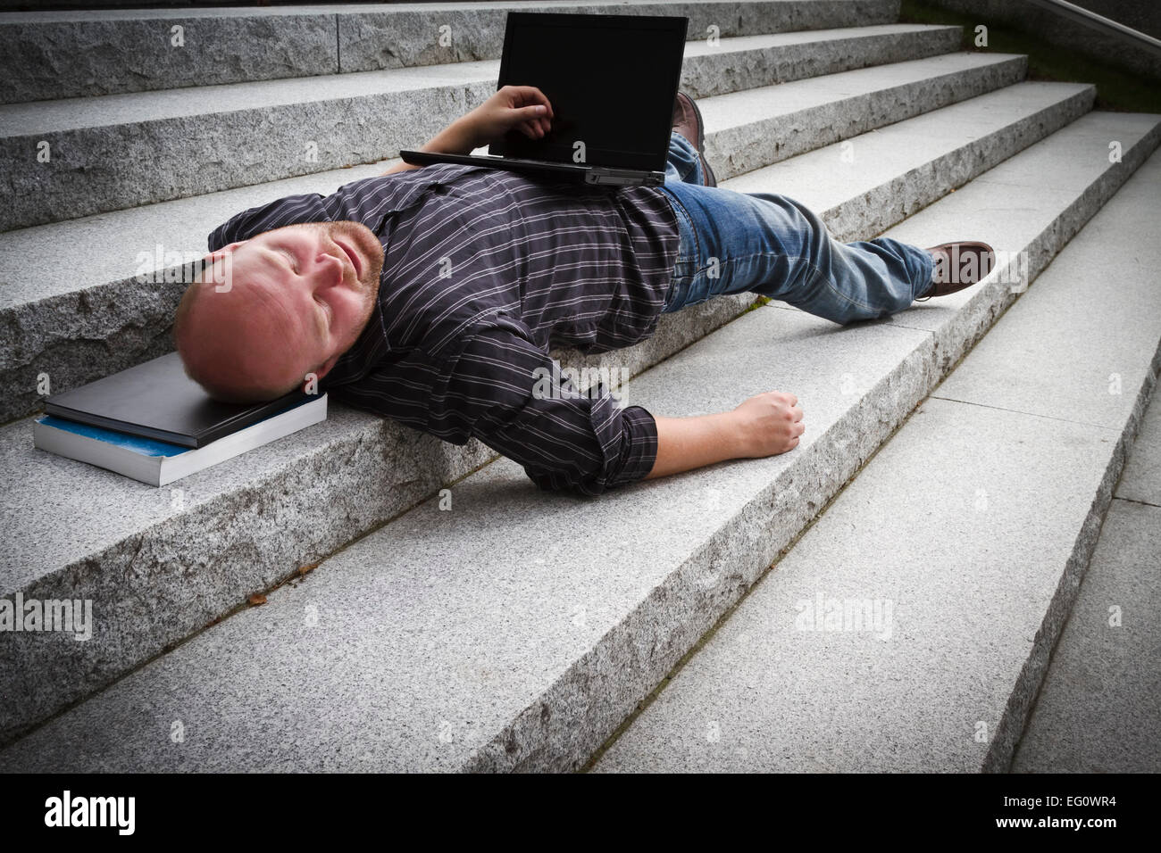 A sleeping / resting / exhausted man working with his computer / laptop