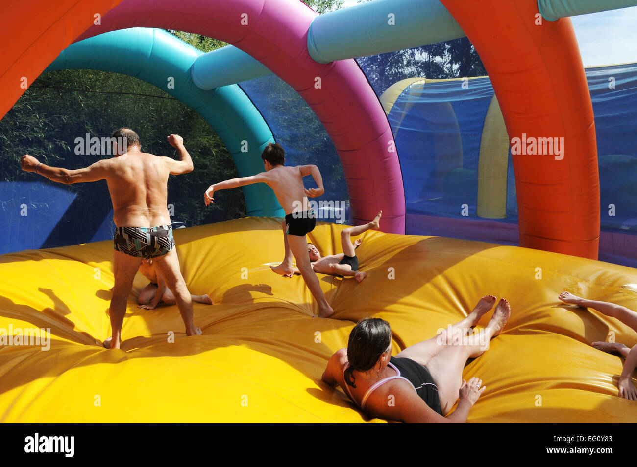 Three generations leaping together on a bouncy castle in Betaille Aquapark in France Stock Photo