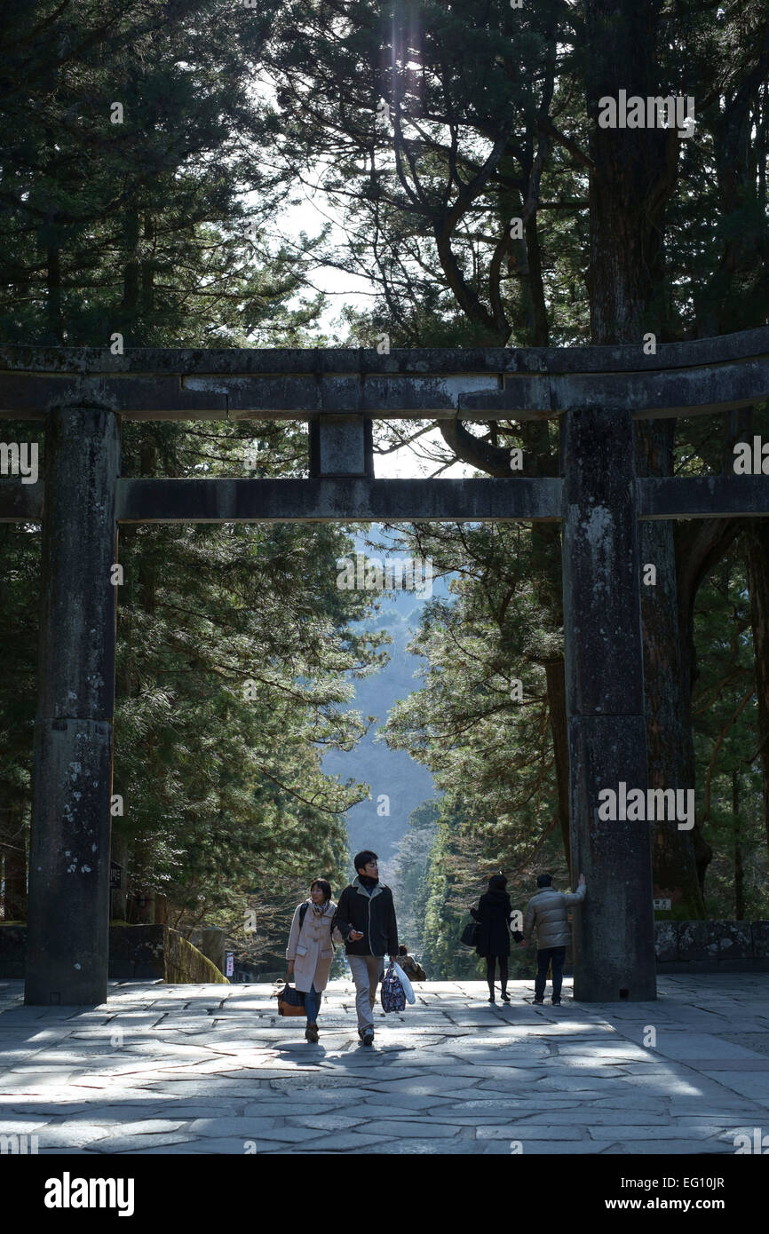 A couple walk holding hands through Tori gate to the Toshogu Shrine. Nikko, Japan Stock Photo