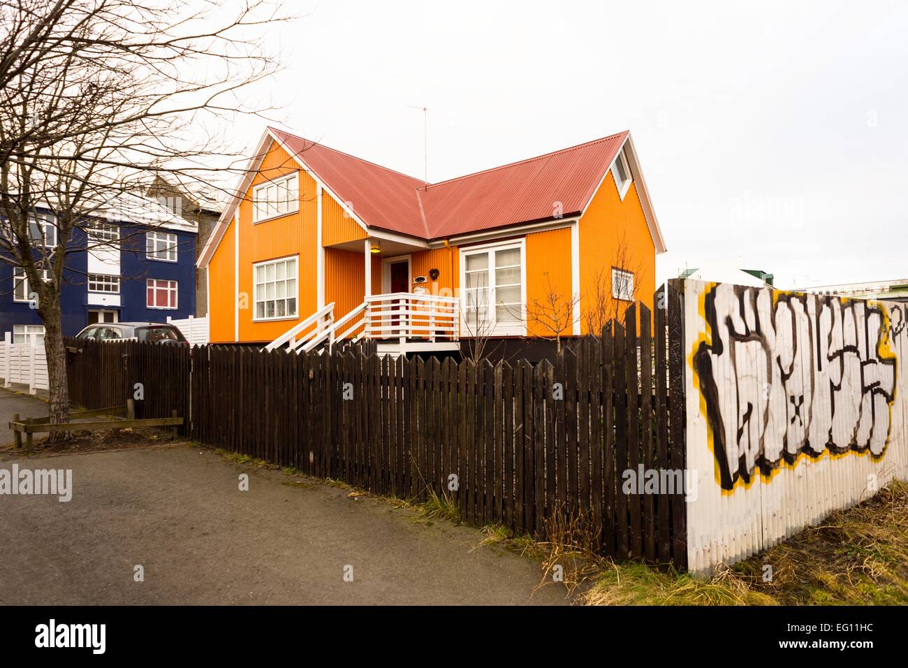 An orange and red painted house surrounded by a fence with graffiti around in Reykjavik, Iceland, 2014. Stock Photo