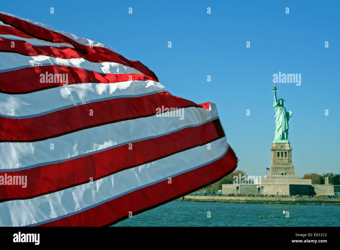 American flag blowing in front of  Statue of Liberty from the Staten Island Stock Photo