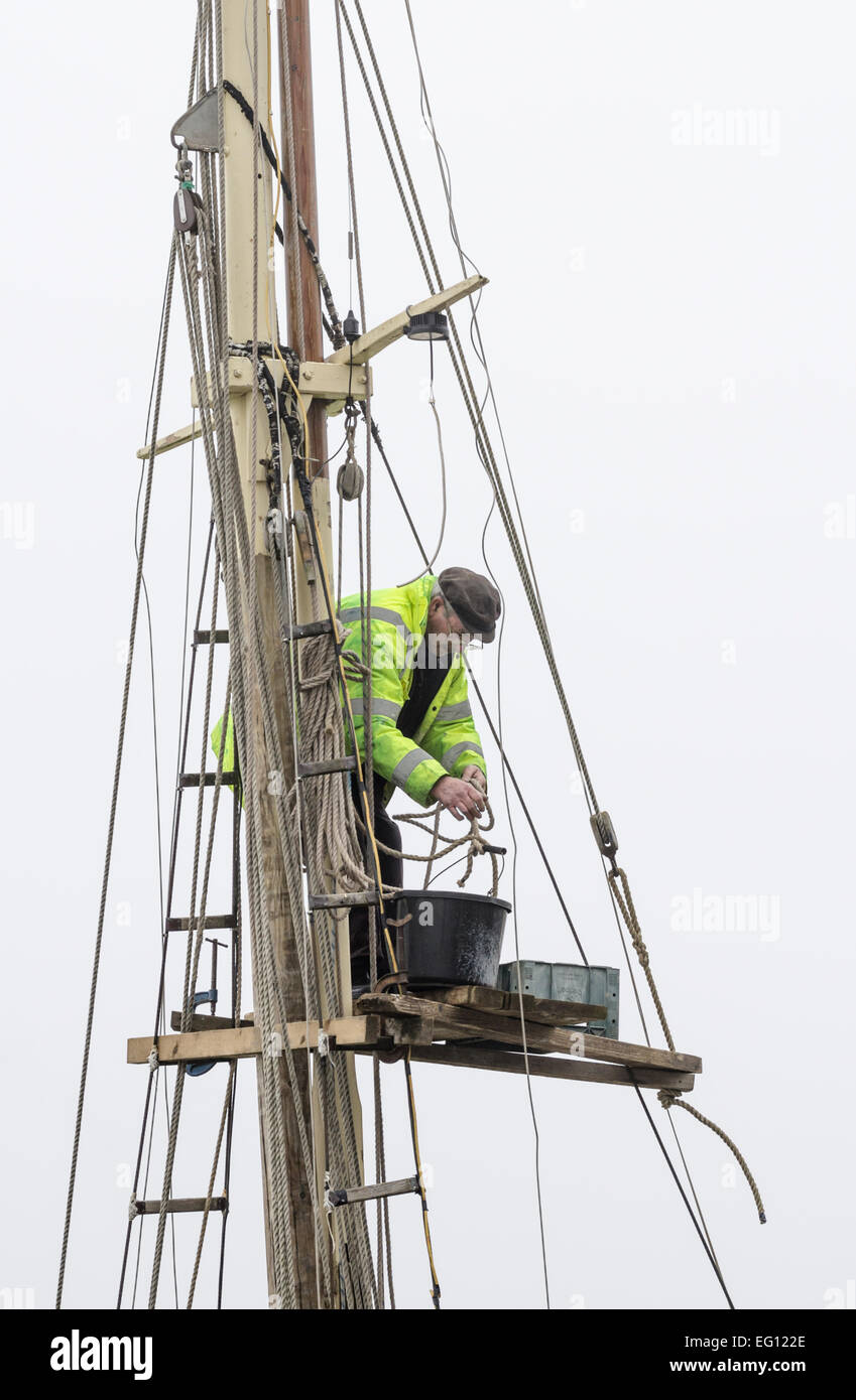 A man working on the mast of a sailing boat. Stock Photo