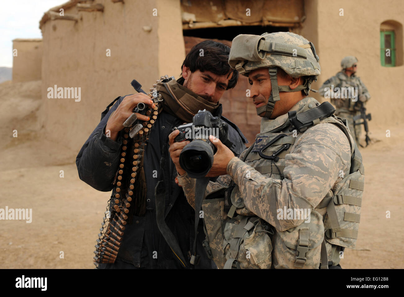 U.S. Air Force Tech. Sgt. Efren Lopez, 4th Combat Camera Squadron, shows digital photographs to an Afghan National Army soldier in the village of Shabila Kalan, Zabul Province, Afghanistan, Nov. 30, 2009.  Staff Sgt. Christine Jones Stock Photo