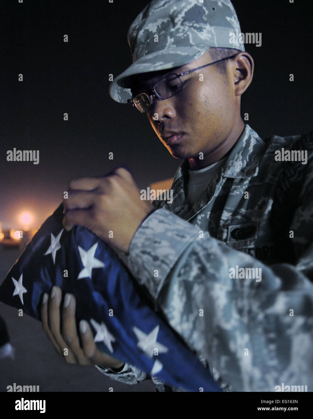 Airman 1st Class Timothy Nguyen learns how to fold up a U.S. Flag to honor fallen military members at an undisclosed location in Southwest Asia August 3. Airman Nguyen is a civil engineer escort with the 379th Expeditionary Civil Engineer Squadron and is deployed from Minot AFB, ND. Senior Airman Katie Gieratz Stock Photo