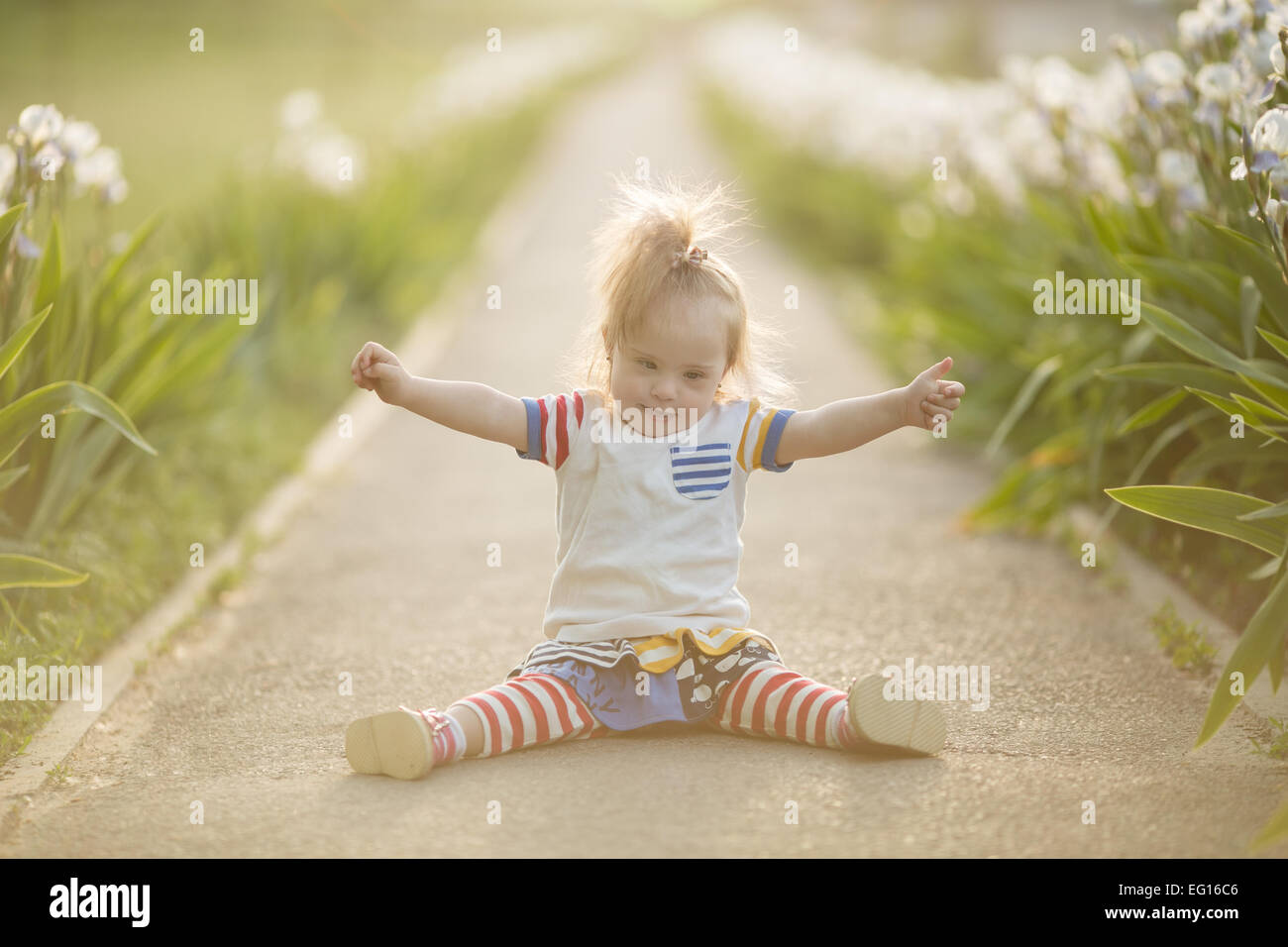 funny girl with Down syndrome sitting in the sunset sun Stock Photo