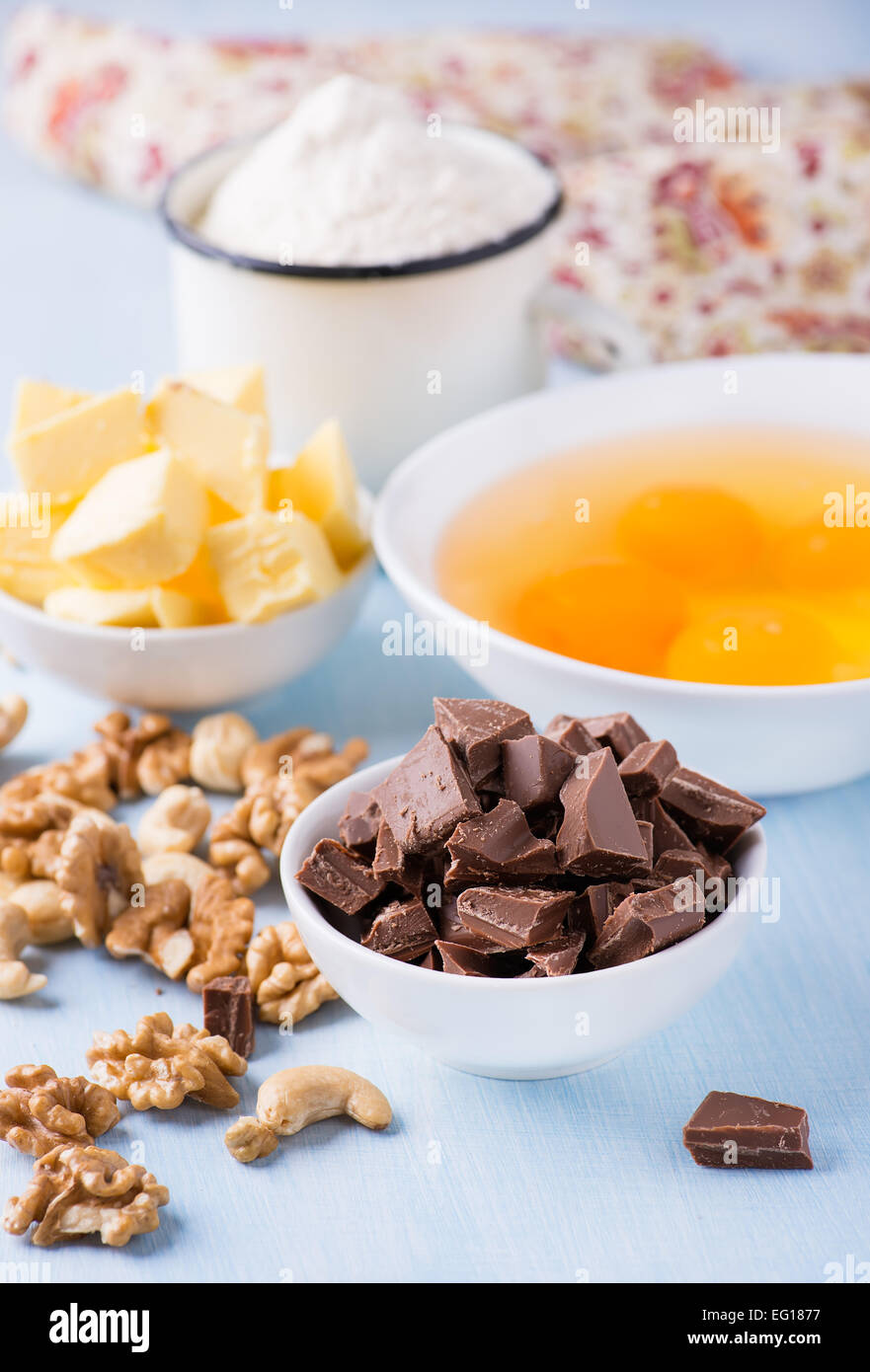 Chocolate chunks, eggs, butter, nuts and cup of flour. Ingredients for baking. Selective focus