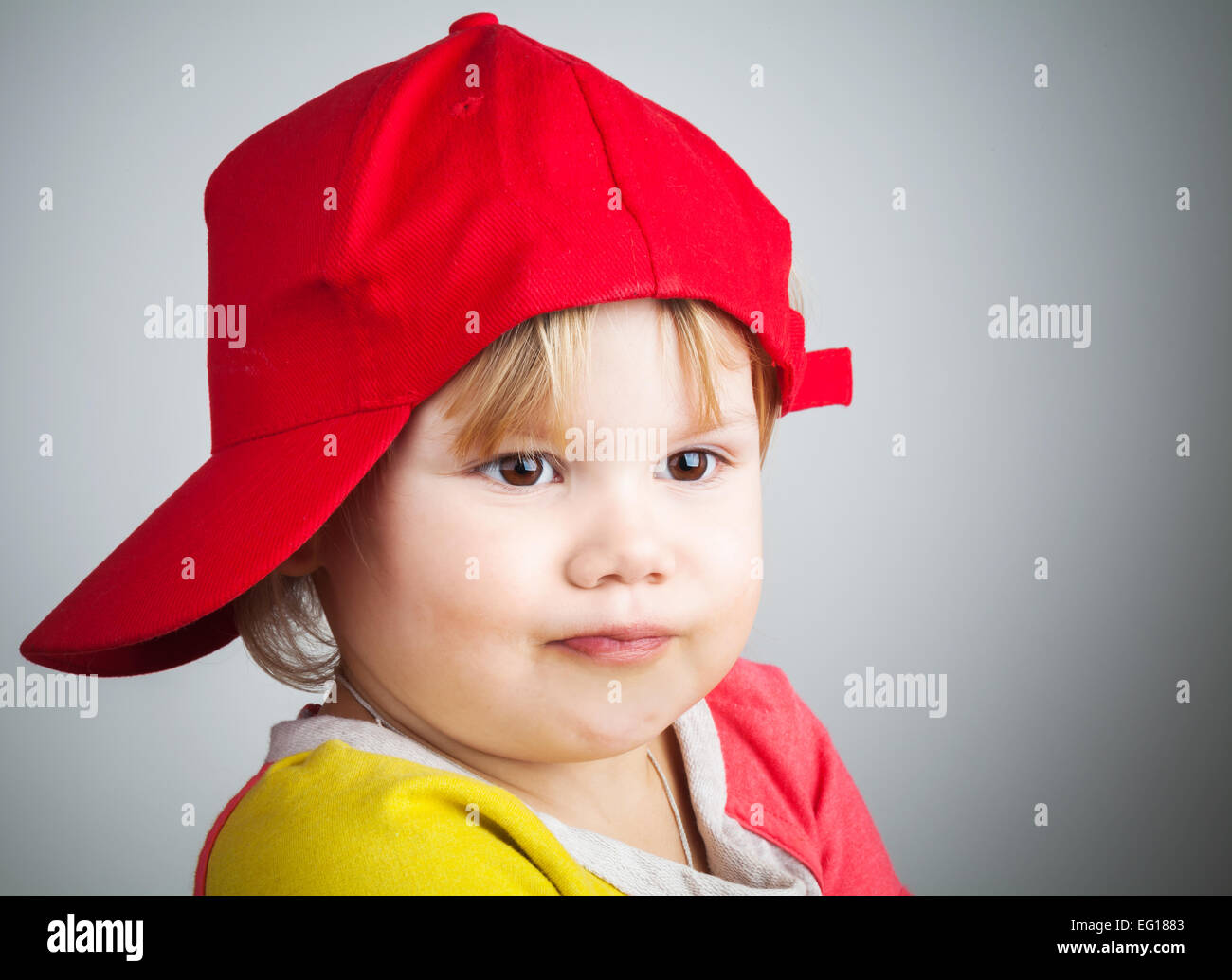 Studio portrait of funny little child in a red baseball cap Stock Photo