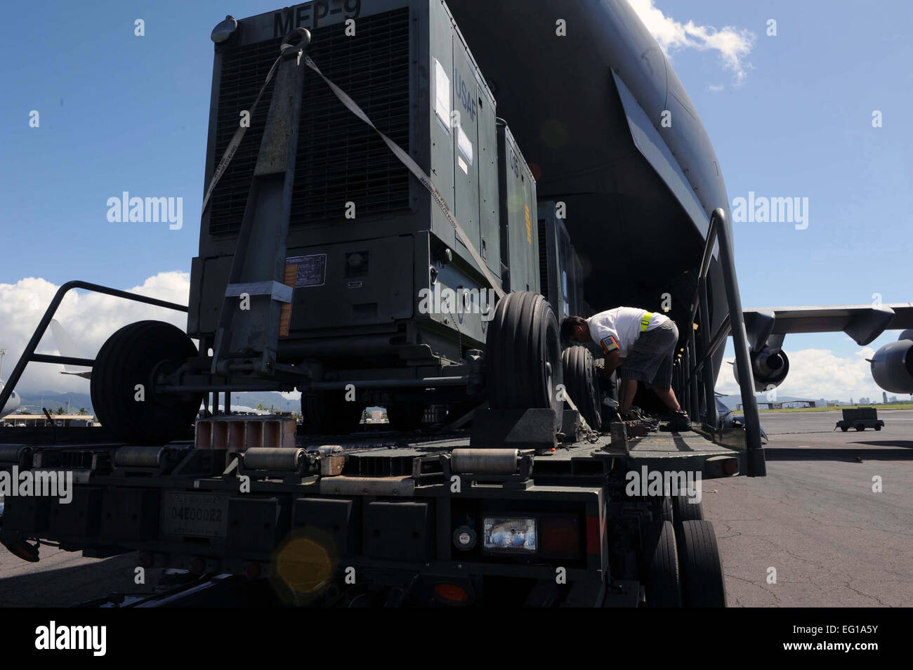 A 735th Air Mobility Squadron ramp service technician loads generators ...