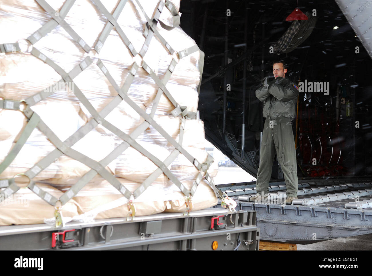 U.S. Air Force Senior Airman Brandon Lee, a 36th Airlift Squadron C-130 Hercules loadmaster from Yokota Air Base, Japan, guides a pallet with humanitarian relief supplies onto a C-130 cargo aircraft at Chitose Air Base, Japan, March 23, 2011. The aircraft transported six pallets carrying 15,000 pounds of blankets, water and rice from the air base to Matsushima, Japan.  Staff Sgt. Robin Stanchak Stock Photo