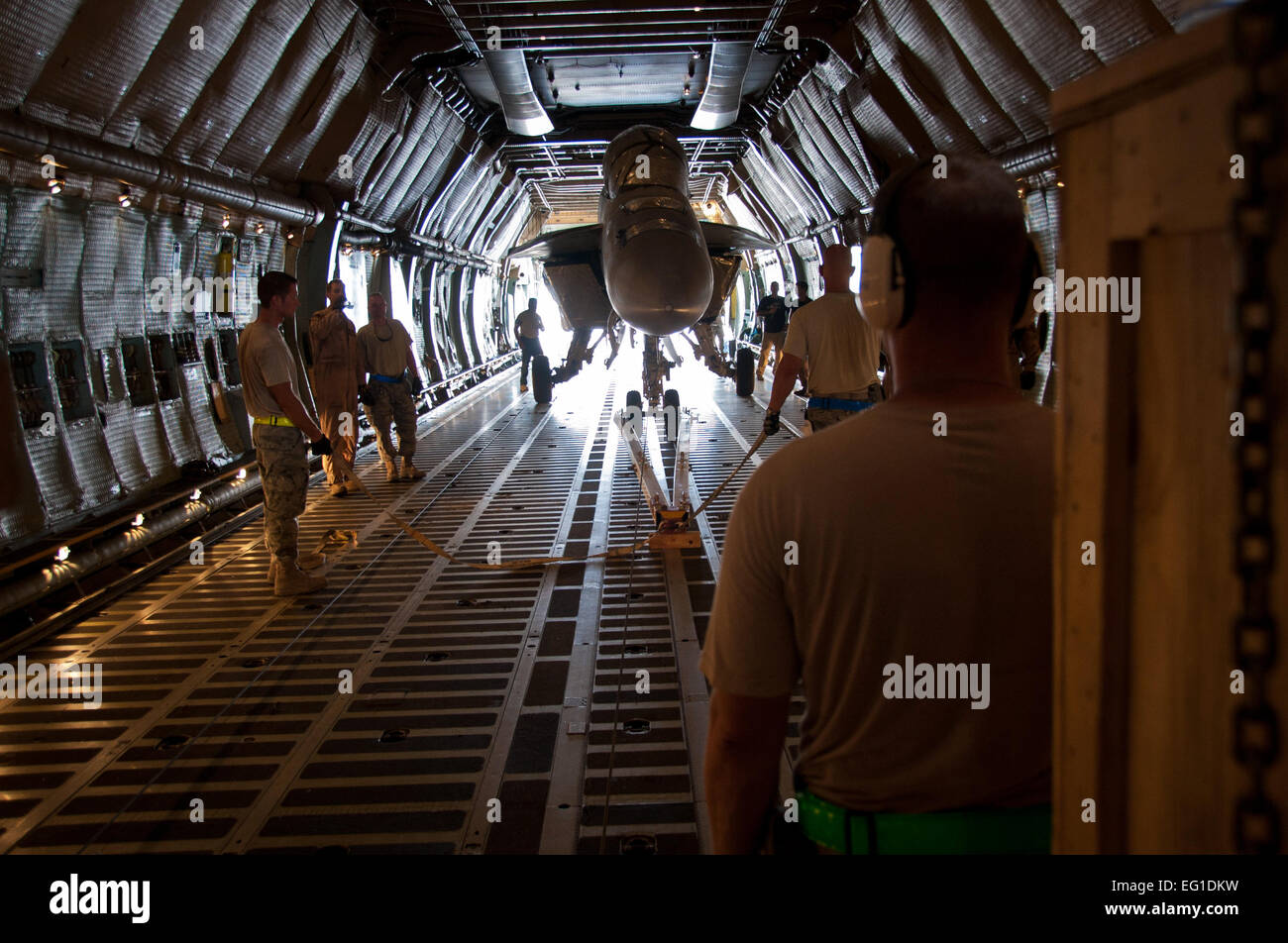 Members of the 451st Expeditionary Logistics Readiness Squadron aerial port flight and 22nd Airlift Squadron prepare to load a U.S. Navy F/A-18 Super Hornet fighter aircraft onto a U.S. Air Force C-5 Galaxy cargo aircraft on Kandahar Airfield, Afghanistan, Aug. 18, 2011. This marked the first time ever that a U.S. fighter jet has been loaded into a cargo aircraft for transport back to the United States. After months of coordination and planning, senior leaders at the Navy's Naval Air Forces and the Air Force's Air Mobility Command approved a plan to transport the aircraft back to its home stat Stock Photo