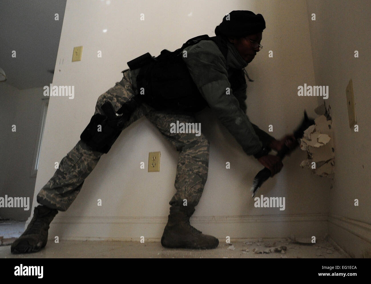 A Security Forces member creates a whole in the wall so that another  member can climb through to another room of the house during Close Quarters Battle Nov. 1, Joint Base Charleston, S.C. CQB training prepares security forces members to handle hostage situations or a threat that is within close range.  While in these situations, the security forces teams learn to neutralize high risk situations with a limited time and within close proximity. The Charleston Fire Department also came out to train them on effectively breaching doors and to conduct other non-conventional  entry/exit techniques. Stock Photo