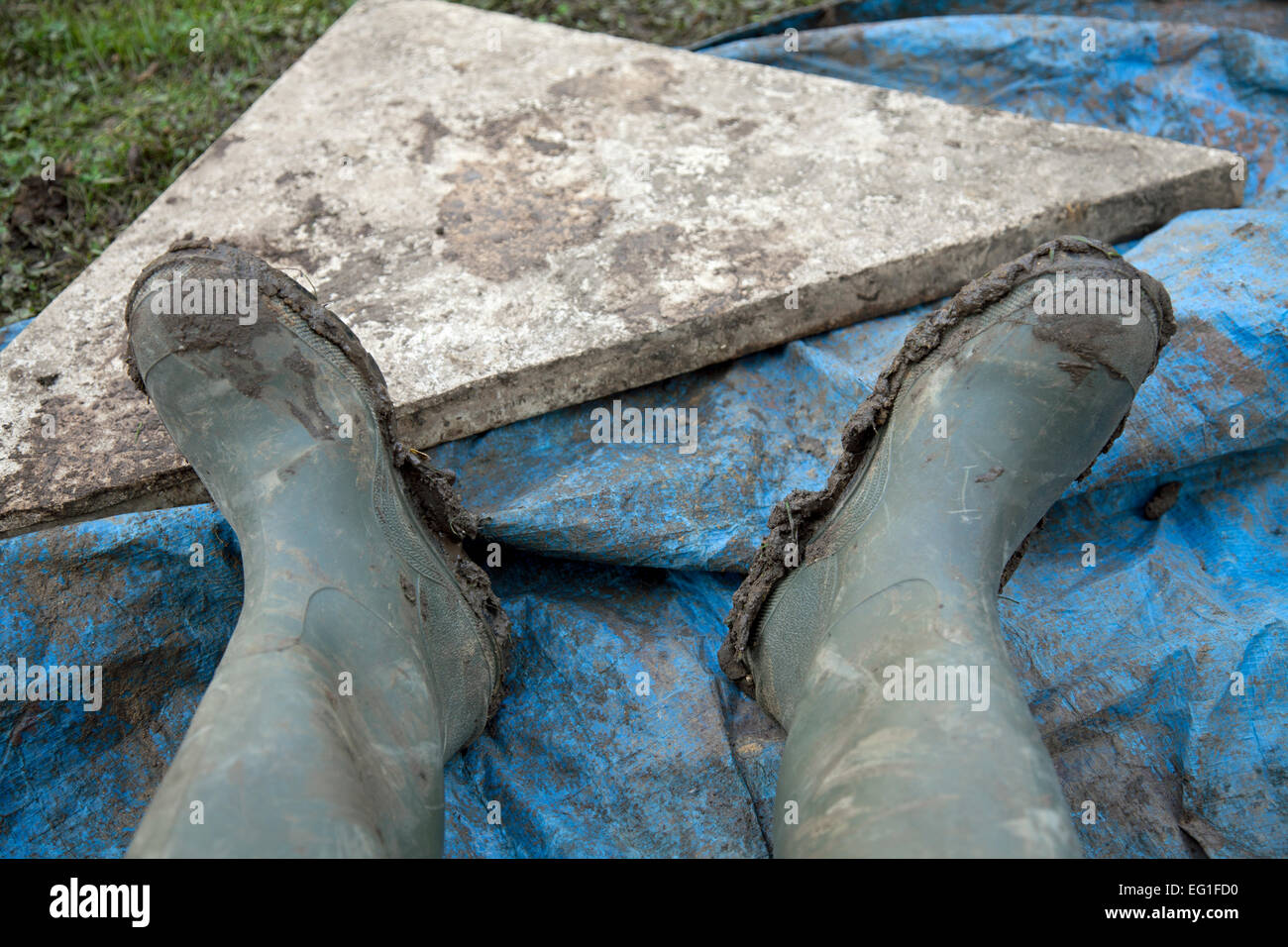 Muddy wellington boots resting on a ground sheet Stock Photo