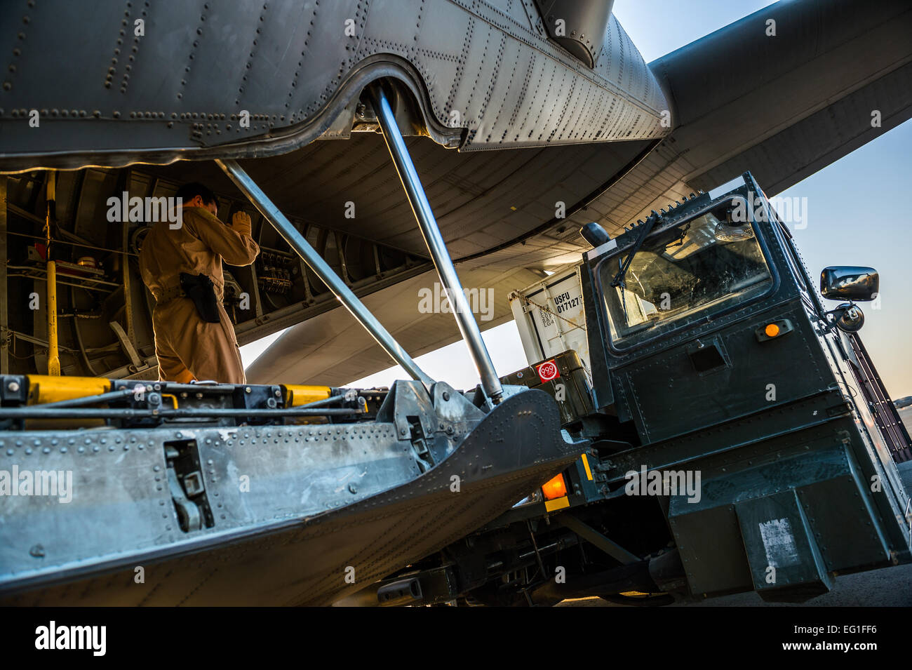 Master Sgt. Scott Francesangeli, 737th Expeditionary Airlift Squadron C-130H loadmaster, directs a K-loader to the back of a C-130H Hercules July 20, 2014, at an undisclosed location in Southwest Asia. Loadmasters ensure all cargo and personnel to be transported on a plane are secured and properly placed to ensure the plane can safely fly. Francesangeli deployed here from the 910th Airlift Wing at Youngstown Air Reserve Station, Ohio, in support of Operation Enduring Freedom.  Staff Sgt. Jeremy Bowcock Stock Photo