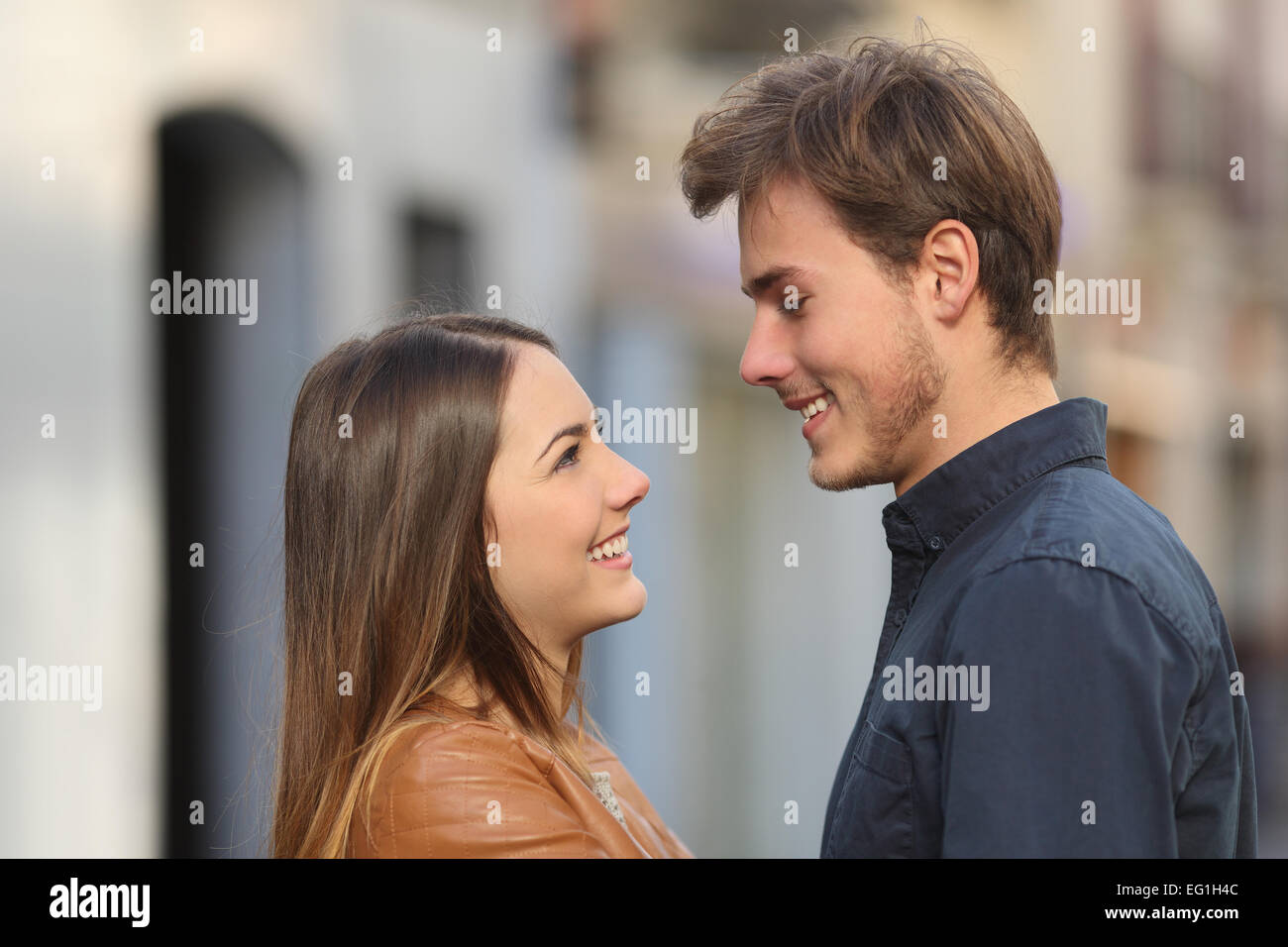 Profile of a happy couple looking each other affectionate in the street Stock Photo