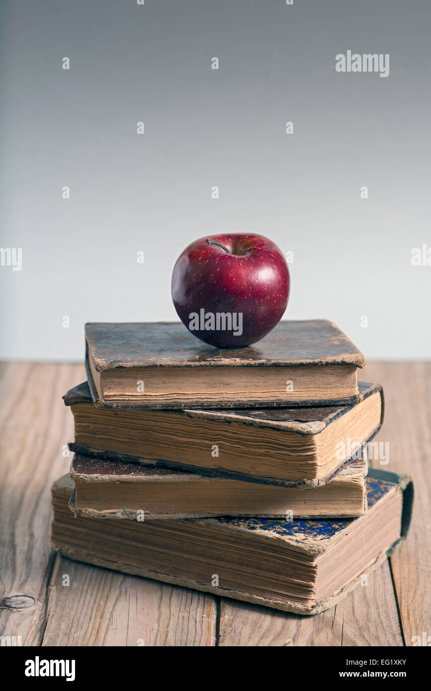 Stack of books and red apple on wooden table. Copy space Stock Photo
