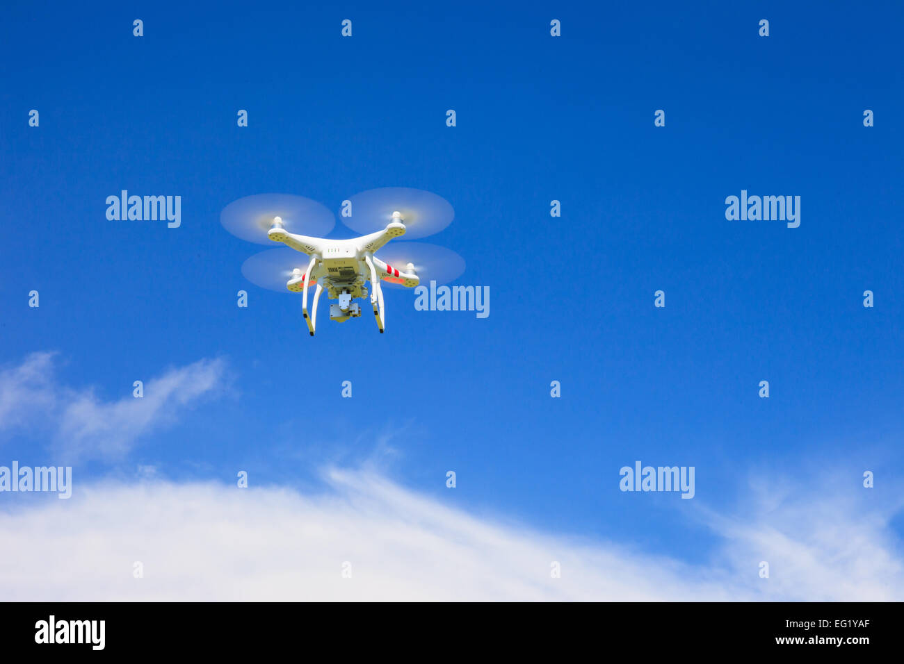 A view from below of a flying drone with a gimbal and camera attached. Drone, photography, flying, surveillance Stock Photo