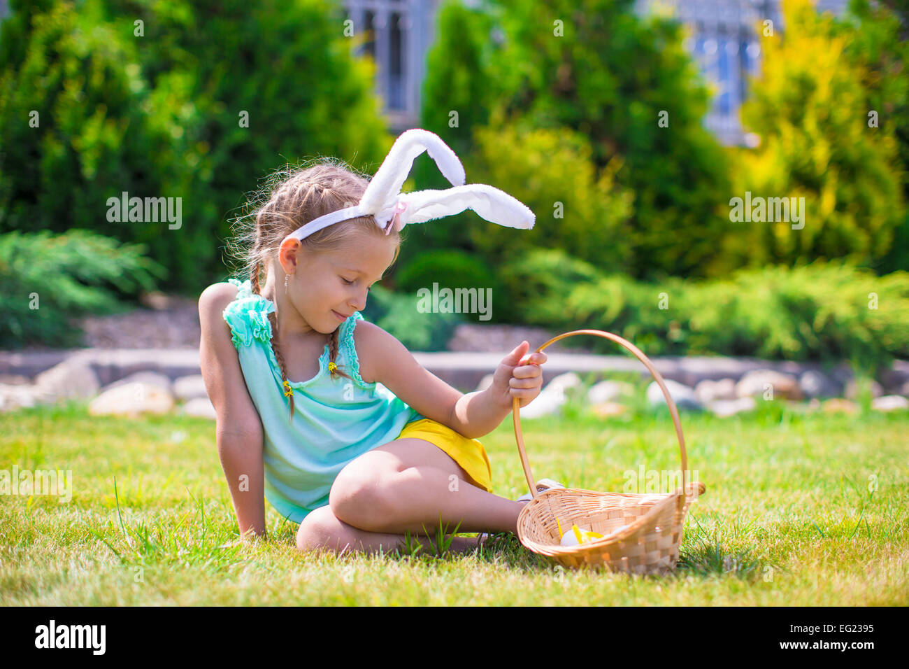 Adorable little girl wearing bunny ears holding basket with Easter eggs ...