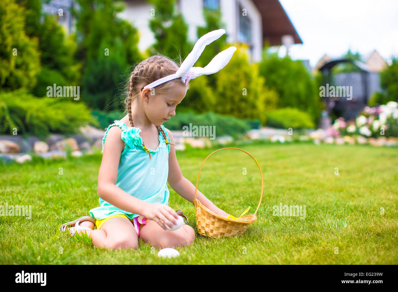 Adorable little girl wearing bunny ears holding basket with Easter eggs ...