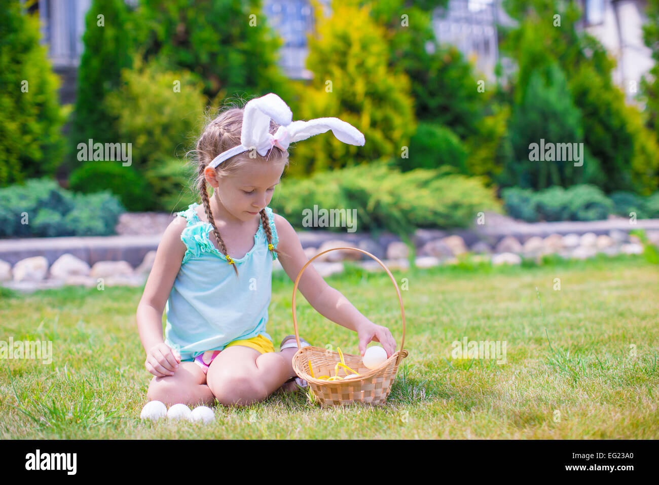 Adorable little girl wearing bunny ears holding basket with Easter eggs ...
