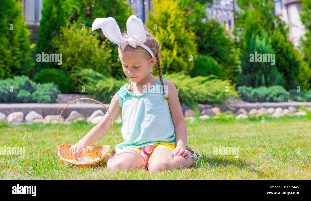 Adorable little girl wearing bunny ears holding basket with Easter eggs ...