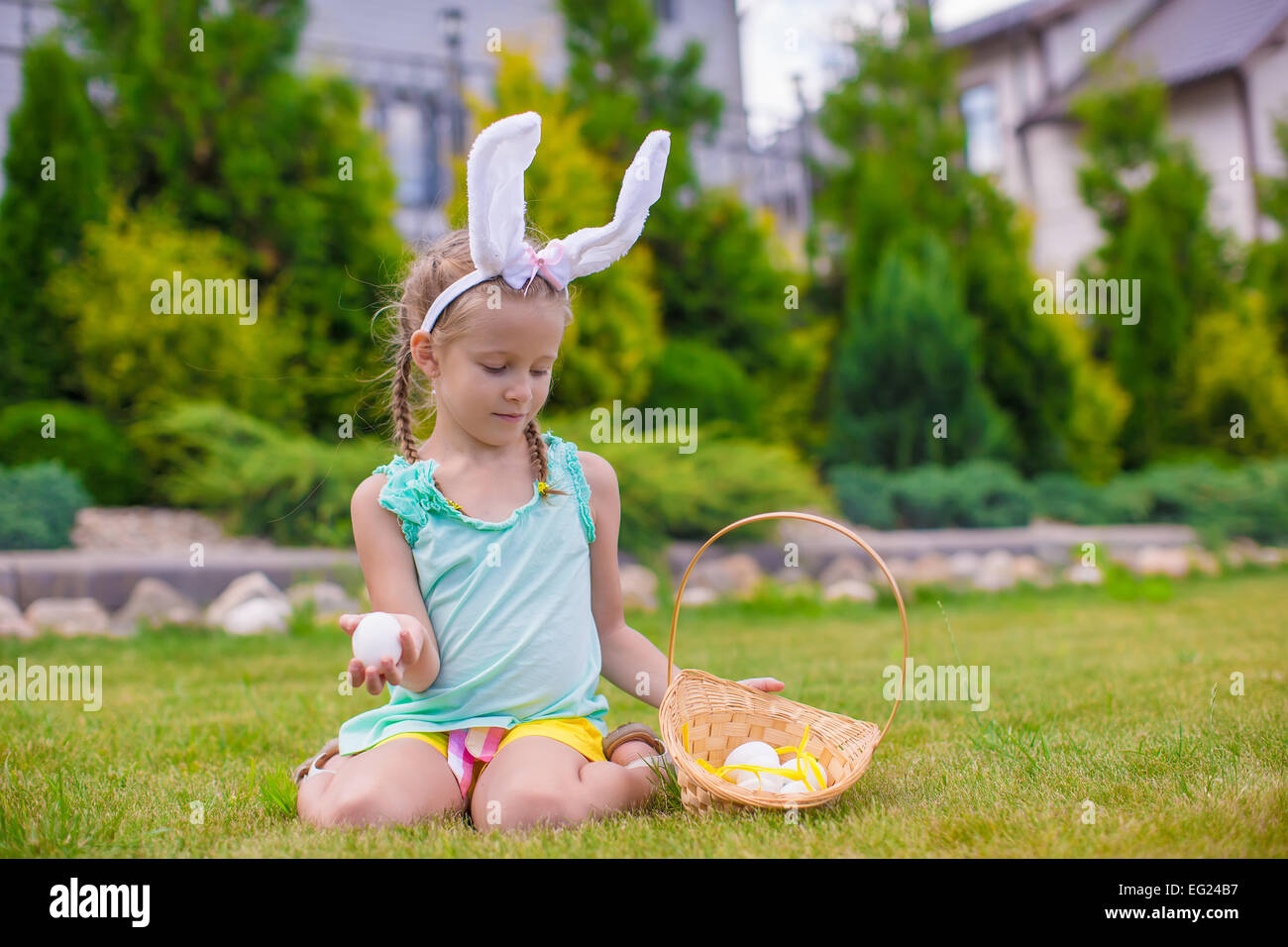 Adorable little girl wearing bunny ears holding basket with Easter eggs ...