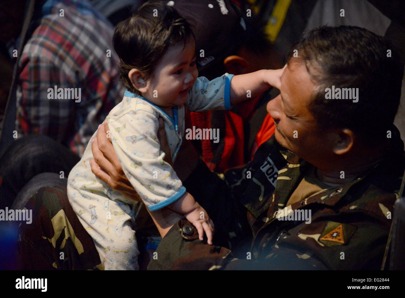 A Philippine Army soldier comforts a baby on a U.S. Air Force C-130H aircraft during an evacuation mission in support of Operation Damayan at Villamor Air Base, Republic of the Philippines, Nov. 19, 2013. Operation Damayan is a humanitarian aid and disaster relief operation led by the Philippine government and supported by a multinational response force.  2nd Lt. Jake Bailey Stock Photo
