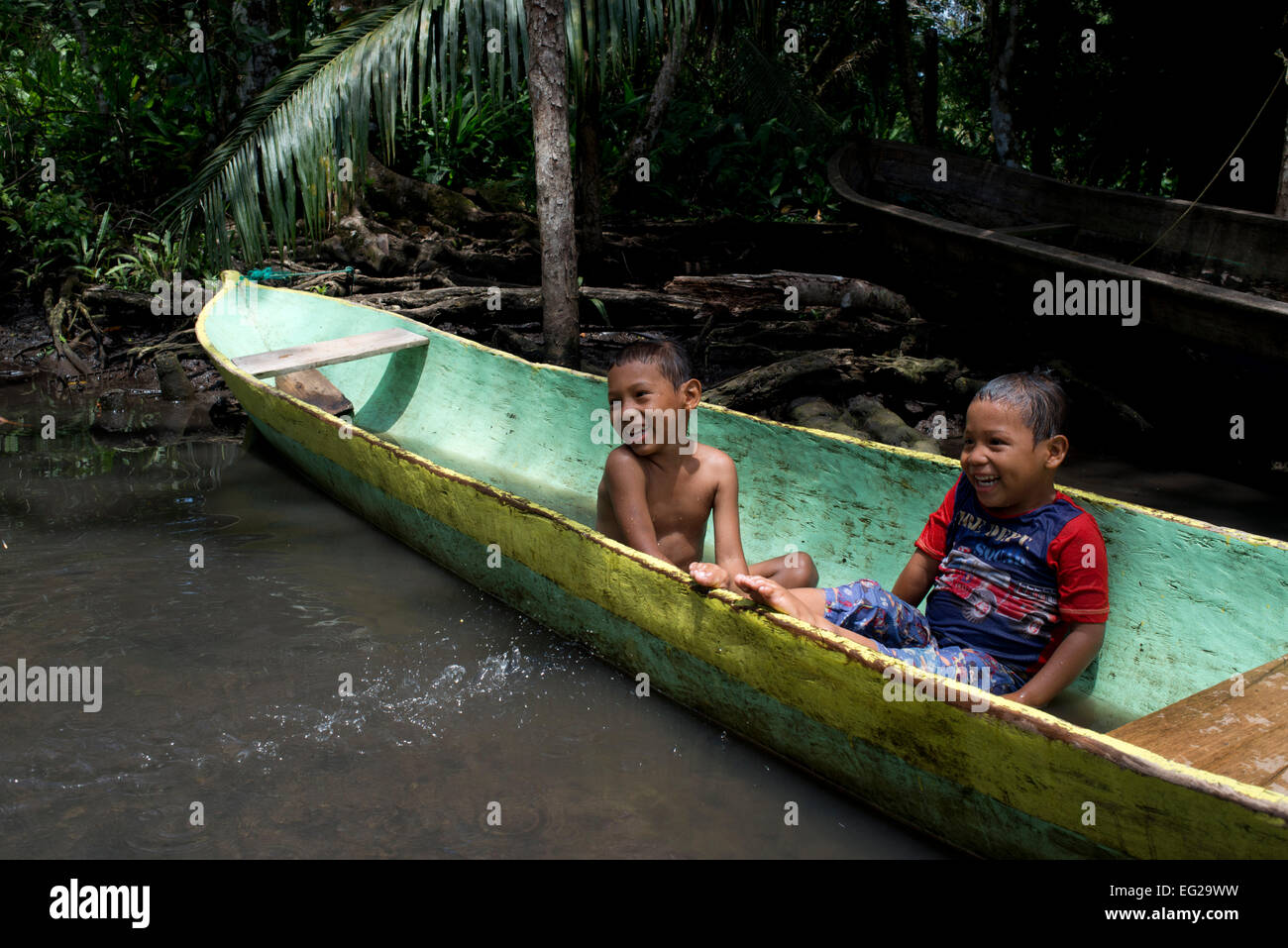 Kids play in one of the local boats used by the Ngobe Indians as their main form of transport, sheltered under a makeshift lean- Stock Photo