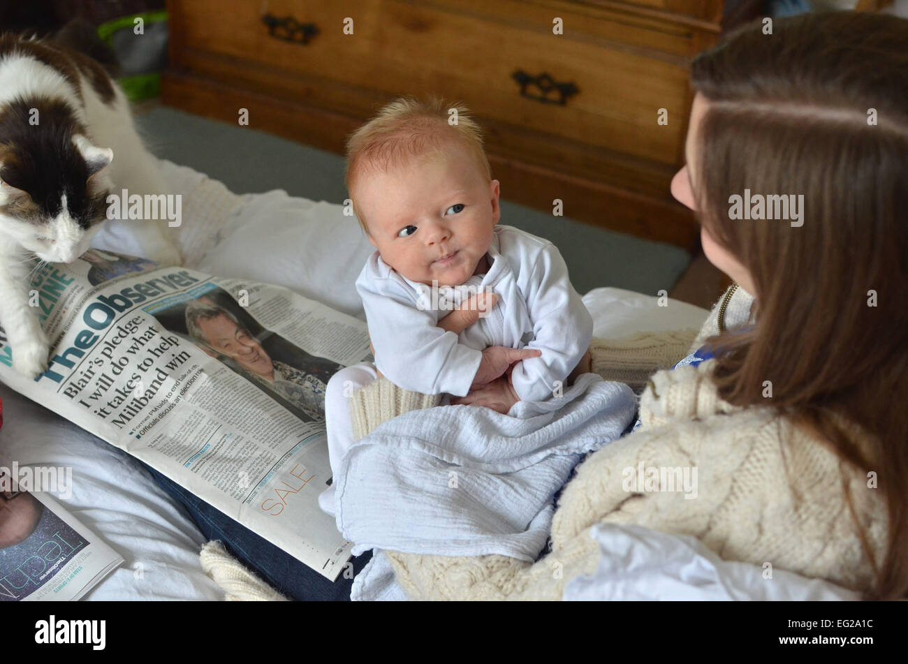 A seven-week old baby sits on his mother's lap on a Sunday morning. Stock Photo