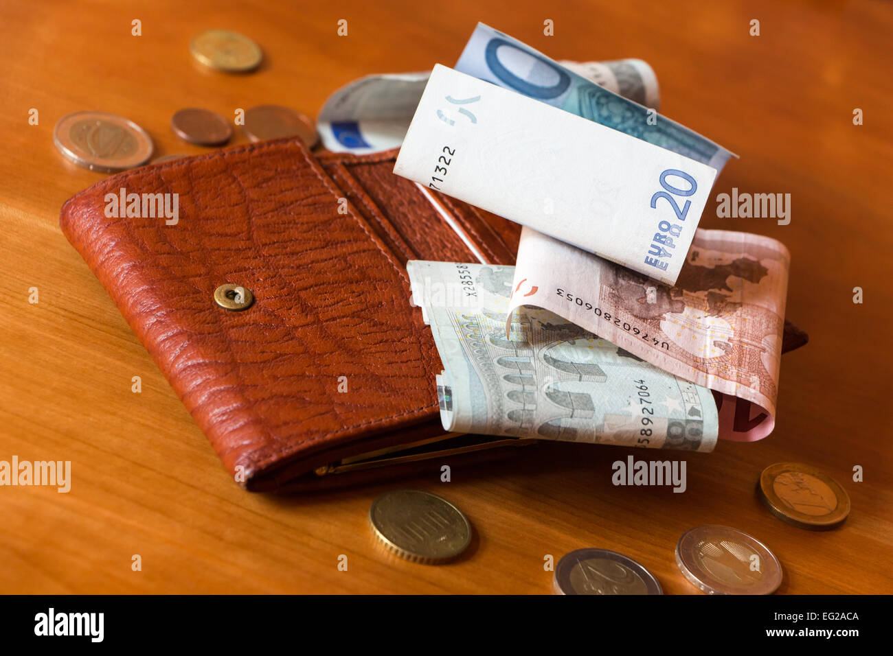 Wallet and some money scattered on a wooden table Stock Photo
