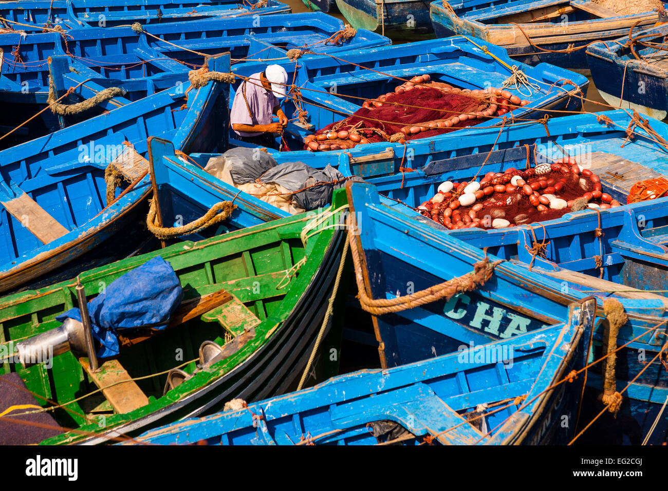 Fisherman working on a blue boat in the port of Essaouira, Morocco Stock Photo