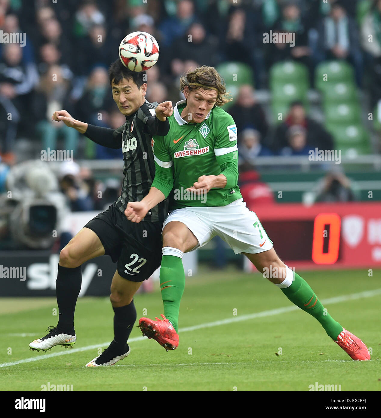 Bremen, Germany. 14th Feb, 2015. Werder's Jannik Vestergaard and Augsburg's Dong Won Ji (L) vie for the ball at the German Bundesliga soccer match between Werder Bremen and FC Augsburg at the Weser Stadium in Bremen, Germany, 14 February 2015. TPhoto: CARMEN JASPERSEN/dpa (EMBARGO CONDITIONS - ATTENTION - Due to the accreditation guidelines, the DFL only permits the publication and utilisation of up to 15 pictures per match on the internet and in online media during the match)/dpa/Alamy Live News Stock Photo