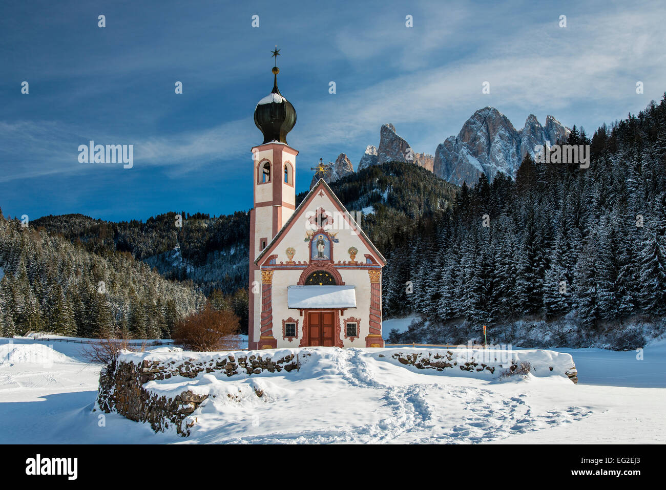 Scenic winter view over St Johann in Ranui mountain church with Puez-Geisler Dolomites behind, Villnoss or Val di Funes, Alto Ad Stock Photo