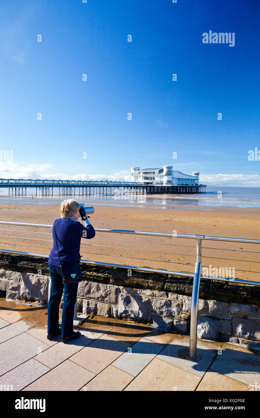 A visitor viewing the new Grand Pier through a telescope at Weston-super-Mare, North Somerset, England, UK Stock Photo