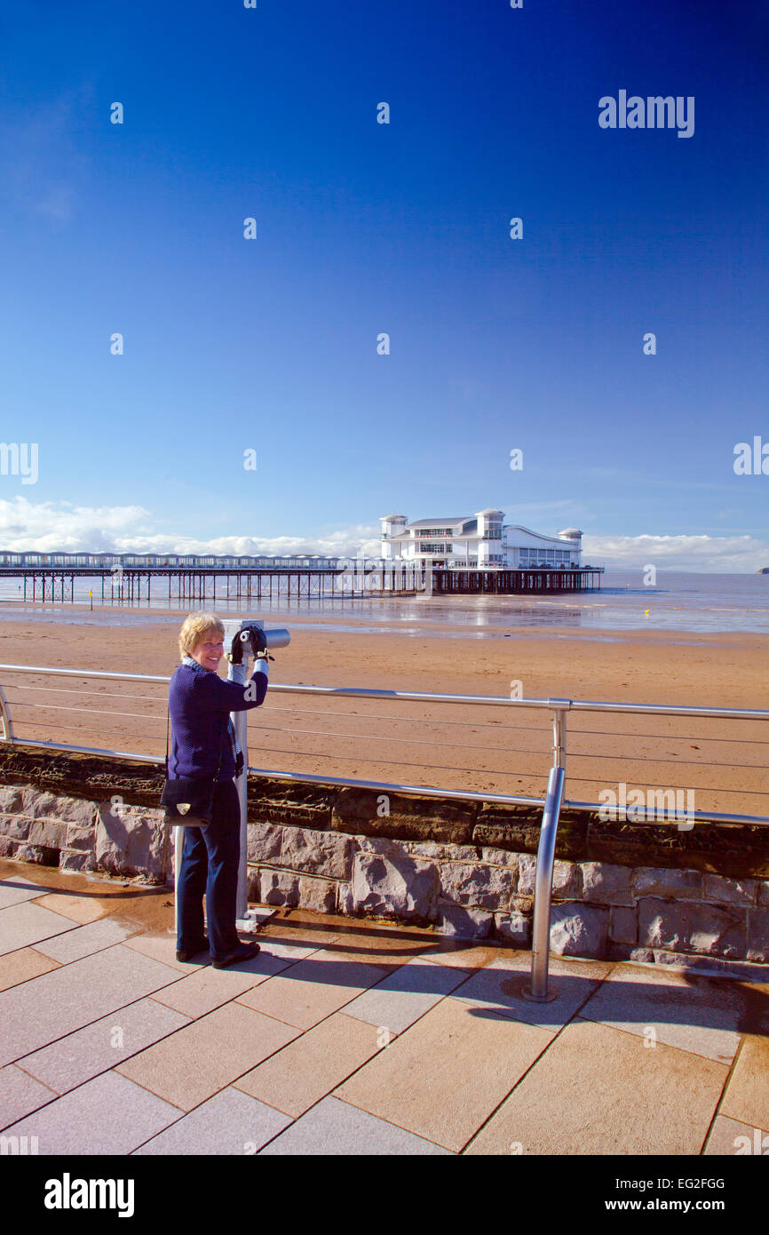 A visitor viewing the new Grand Pier through a telescope at Weston-super-Mare, North Somerset, England, UK Stock Photo