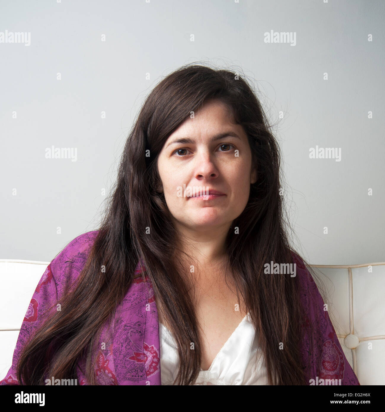 Head and shoulders portrait of woman with long brown hair looking at camera wearing nightgown and housecoat Stock Photo