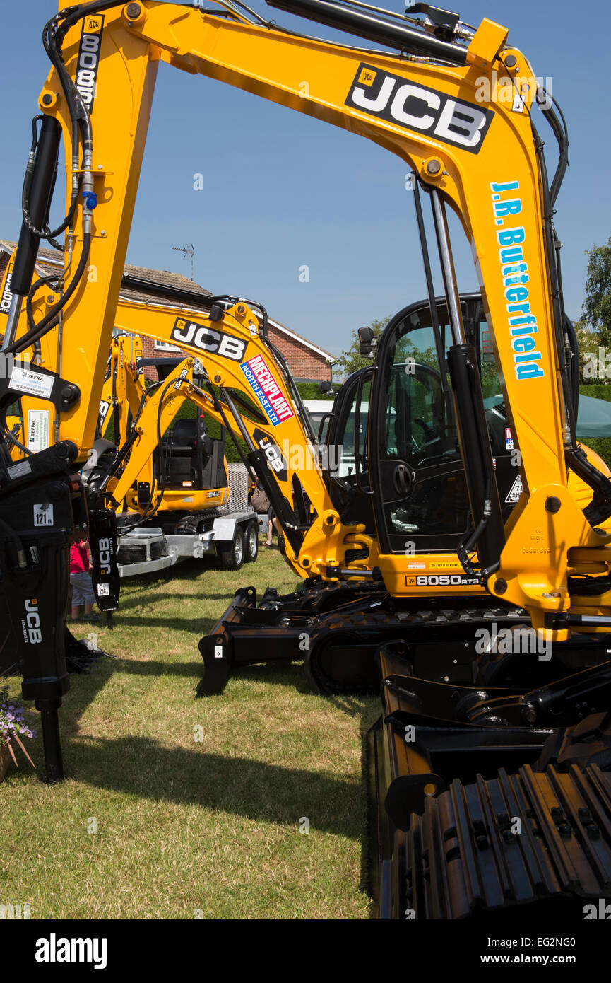Under deep blue sky, close-up view of clean bright yellow JCB 8085 midi excavators parked on display - trade stand, Great Yorkshire Show, England, UK. Stock Photo