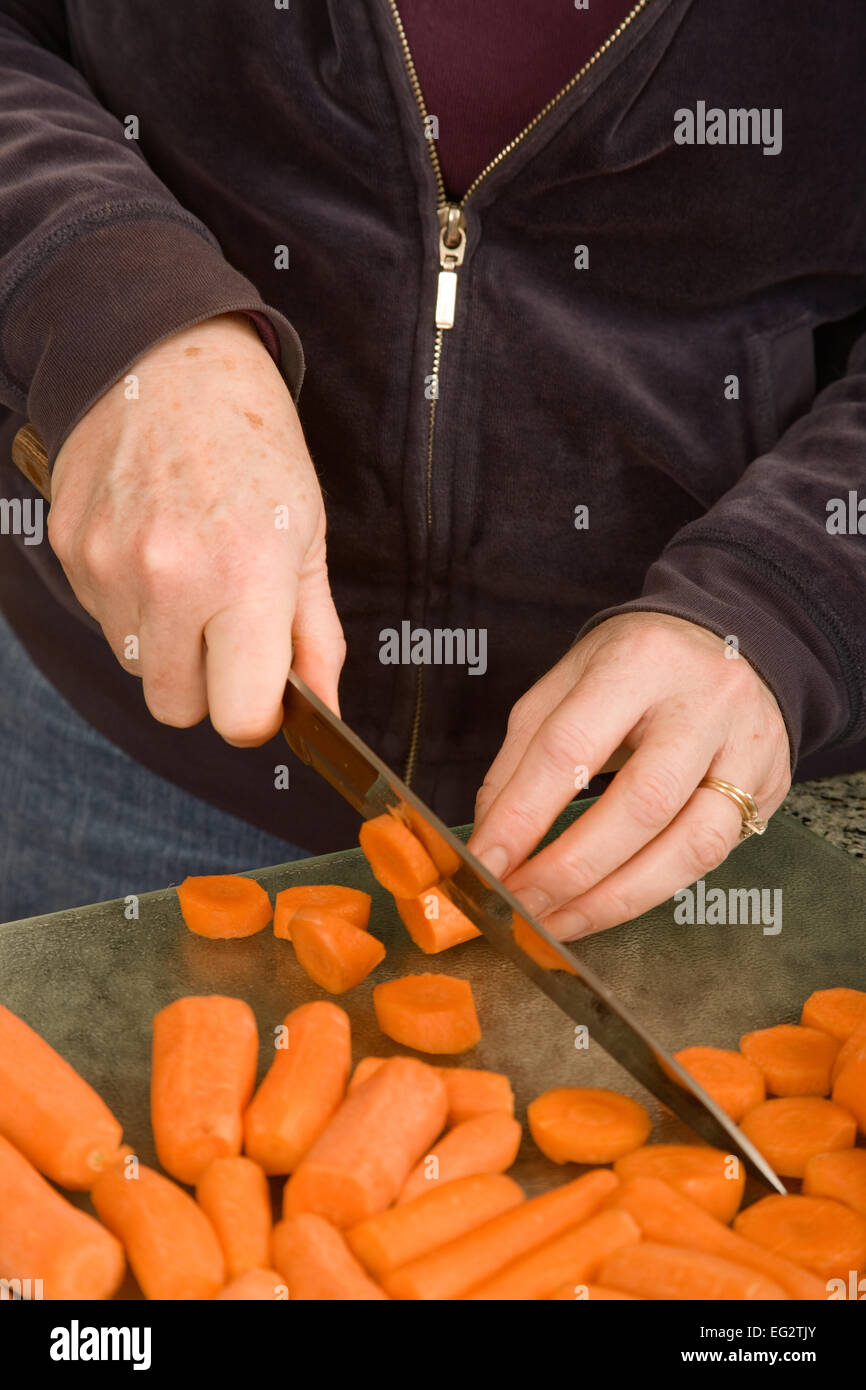 Woman chopping carrots with a knife in preparation for blanching and