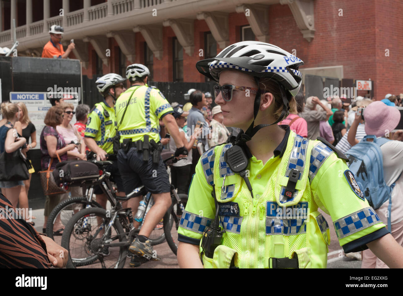 Female Western Australia police bicycle officer with two male colleagues in the background Stock Photo