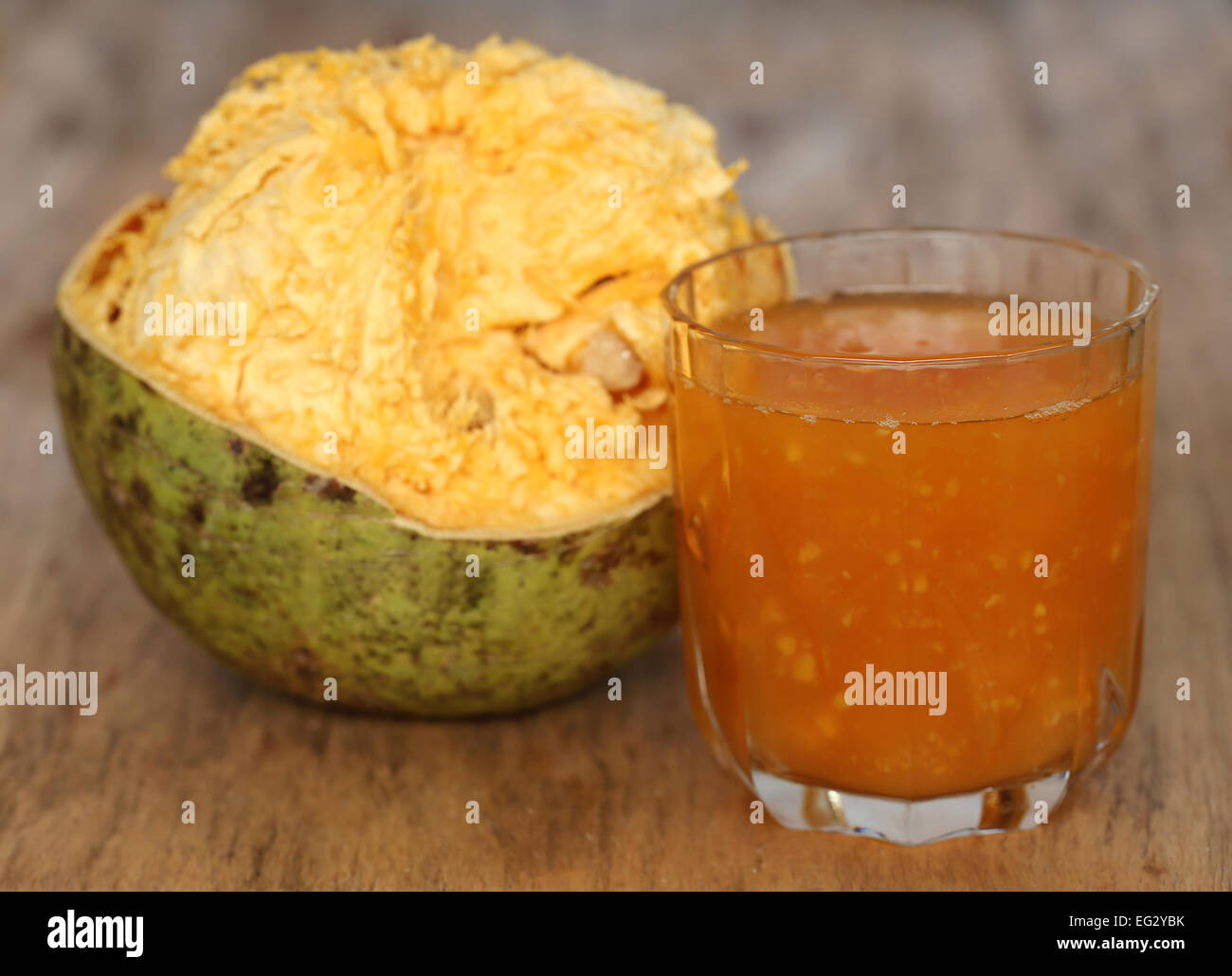 Medicinal Bael fruit with juice on wooden surface Stock Photo