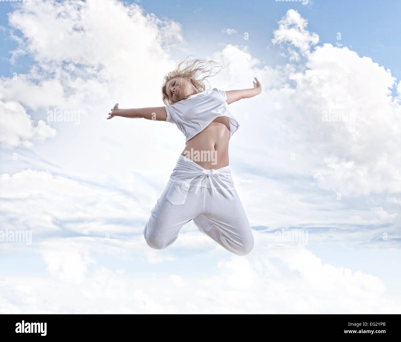 Portrait of young jumping woman on blue sky background Stock Photo - Alamy